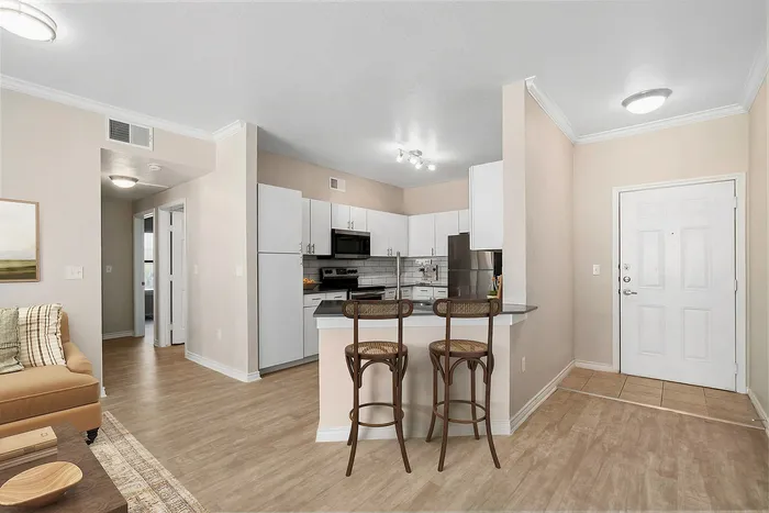 Modern open-concept kitchen and living area with sleek countertops, bar stools, and stylish cabinetry.