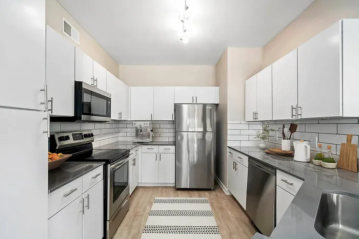 Modern kitchen with sleek stainless steel appliances, elegant white cabinetry, and a chic monochrome design.