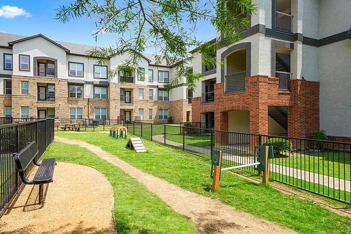 Inviting apartment community with modern architecture, lush green lawns, and a charming outdoor seating area.