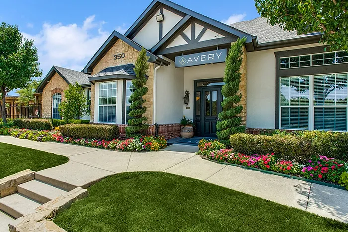 Charming and elegant apartment exterior with lush landscaping, vibrant flowers, and inviting entrance at Avery residences.