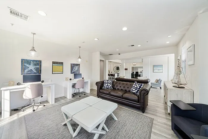 Modern living room with chic leather sofa, dual workstations, and elegant decor, perfect for relaxation and productivity.