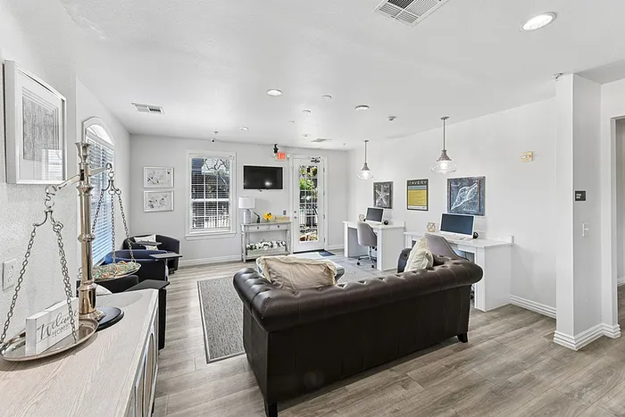 Bright and inviting living space with modern furnishings, featuring a comfortable leather sofa, workstations, and elegant decor.