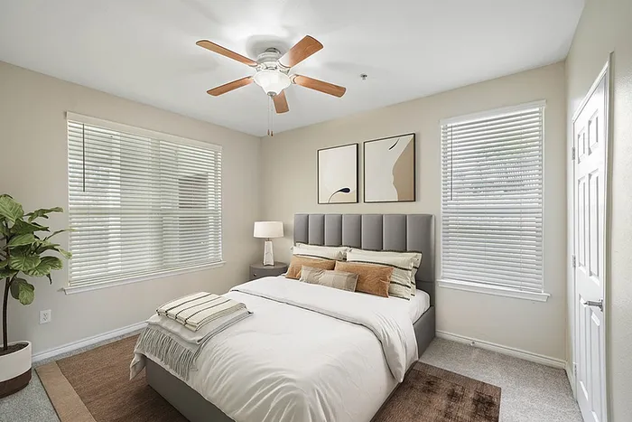 Inviting bedroom with elegant decor, cozy bed, and abundant natural light from large windows, creating a serene retreat.