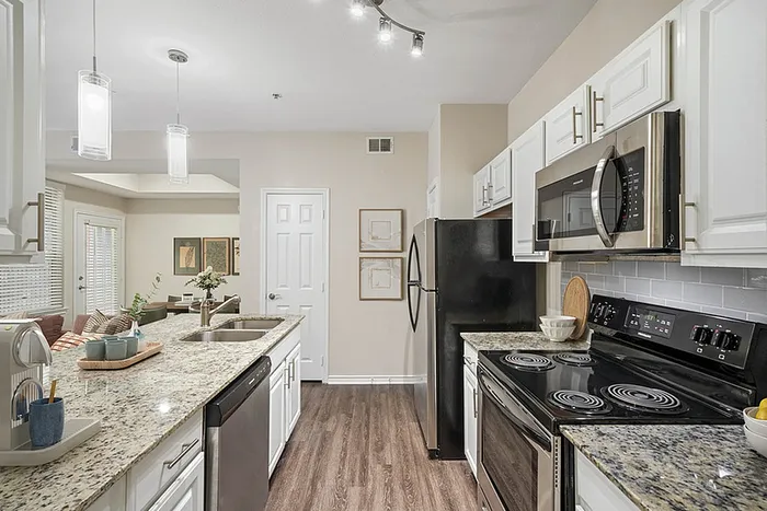 Elegant kitchen with modern appliances, granite countertops, and stylish lighting, seamlessly opening to a cozy living area with chic decor.
