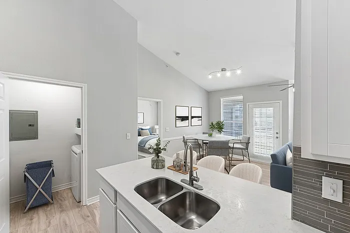Modern open-plan apartment with stylish kitchen island, bright dining area, and cozy living space, featuring elegant decor and natural light.