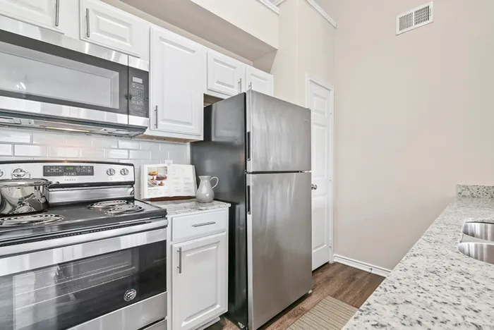 Modern kitchen with sleek stainless steel appliances, elegant white cabinetry, and granite countertops.