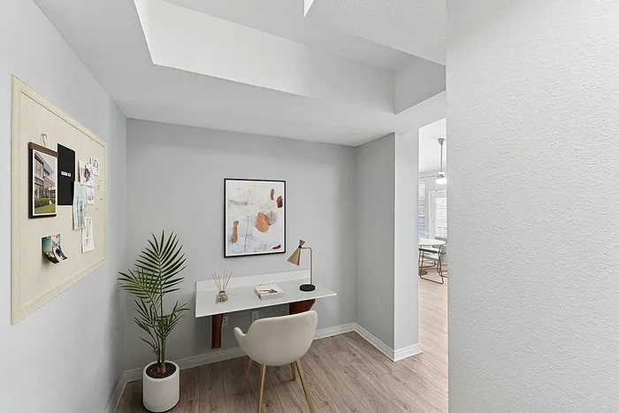 Chic and modern workspace nook with a sleek desk, inspiring wall art, and vibrant plant in a stylish apartment.