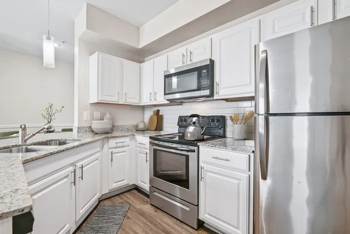 Modern kitchen with sleek stainless steel appliances, elegant white cabinetry, and stylish granite countertops.