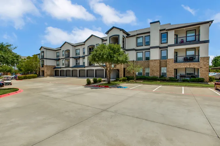 Charming apartment complex featuring modern architecture, lush greenery, garages and ample parking in a serene neighborhood.