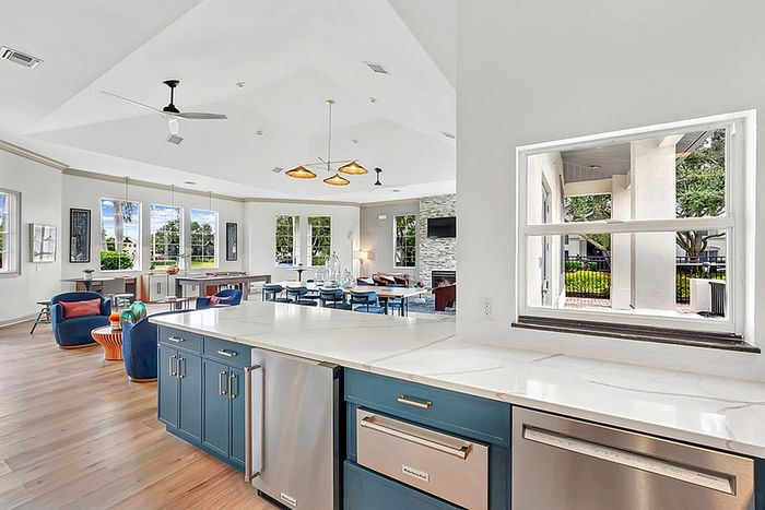 Clubhouse kitchen with modern blue cabinets, sleek countertops, and stylish lighting, complemented by large windows offering scenic views.
