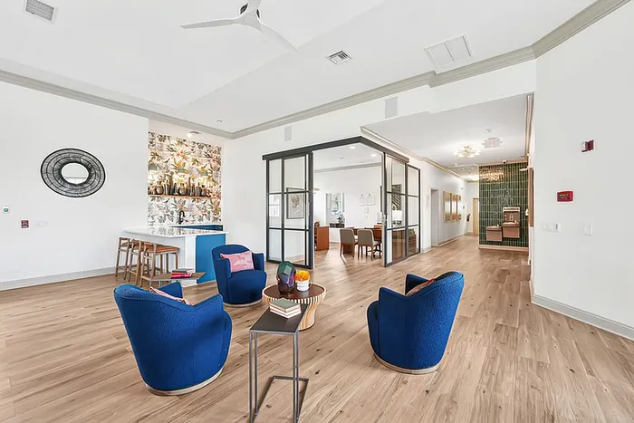 Clubhouse featuring vibrant blue chairs, wooden flooring, and a stylish bar area with floral accents.