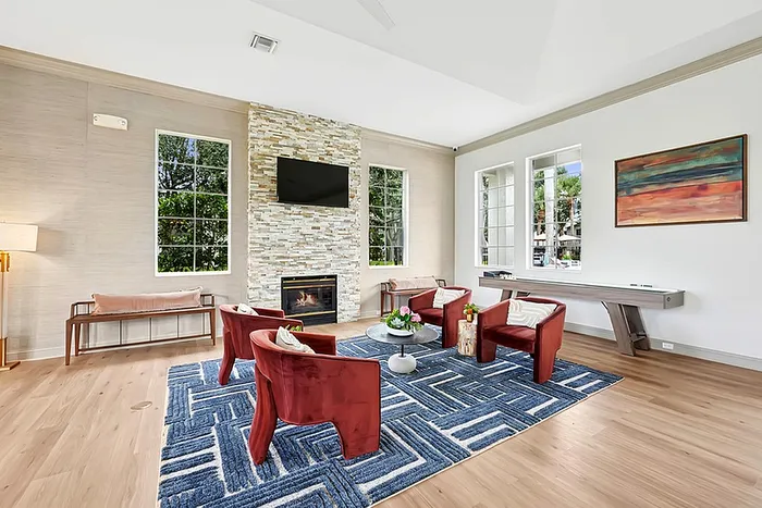 Community clubhouse with red armchairs, chic fireplace, and large windows providing ample natural light.