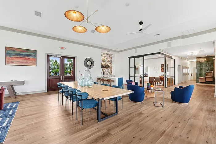 Clubhouse with a long wooden dining table, plush blue chairs, and stylish pendant lighting, perfect for gatherings.