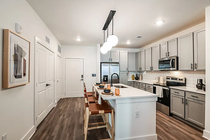 Modern kitchen with sleek gray cabinetry, stainless steel appliances, and an island with stylish lighting.