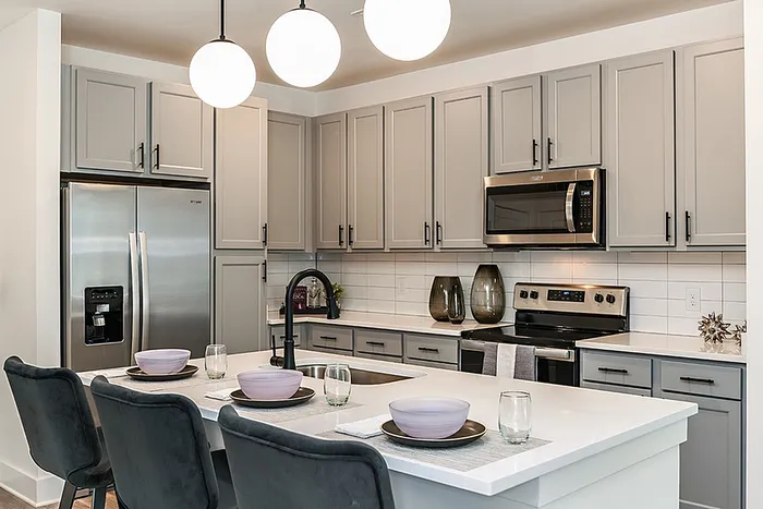 Modern kitchen with sleek cabinetry, stainless steel appliances, and a stylish island with seating for three.