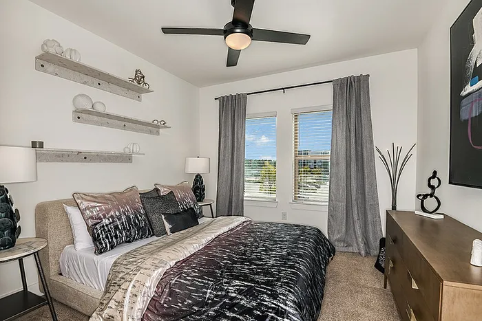 Chic bedroom with stylish decor, featuring a cozy bed, modern wall shelves, and large windows with a serene view.