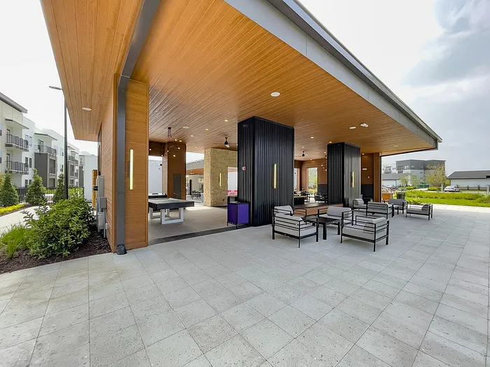 Modern outdoor lounge area with sleek seating and a stylish wooden overhang, perfect for relaxation and entertaining.