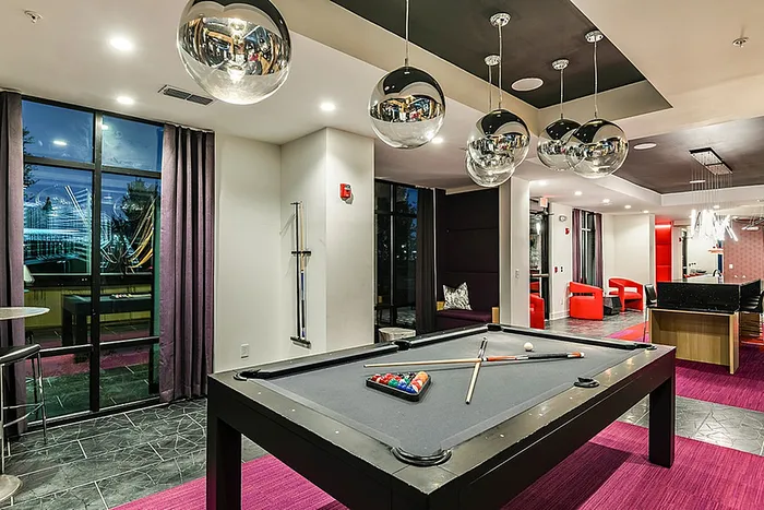 Chic clubhouse lounge with a sleek pool table, modern decor, and vibrant red accents; perfect for entertainment and relaxation.