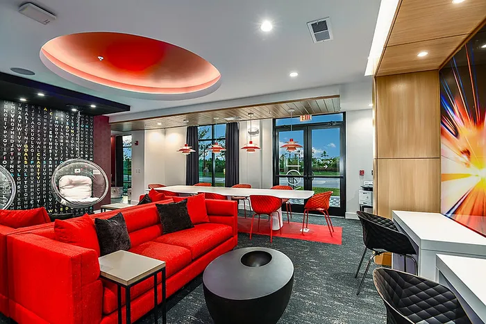 Luxurious clubhouse lounge area with vibrant red seating, modern lighting, and stylish decor, perfect for relaxation and social gatherings.