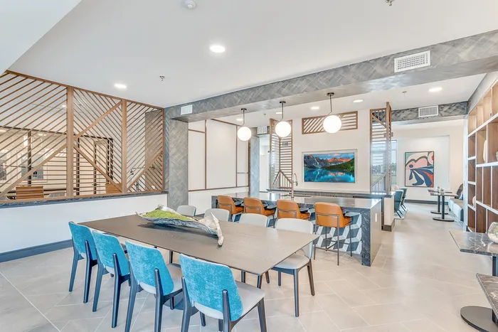 Modern communal area with stylish seating, large wall art, and natural light, featuring a sleek bar with chic lighting.