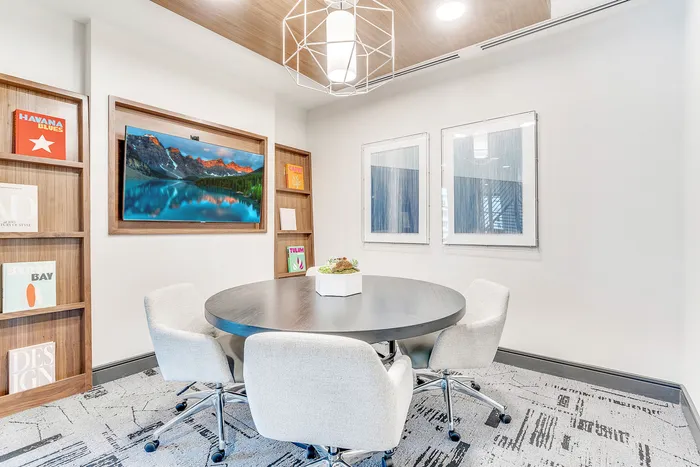 Contemporary meeting room with a round table, plush chairs, elegant wall art, and ambient lighting, perfect for creativity and collaboration.