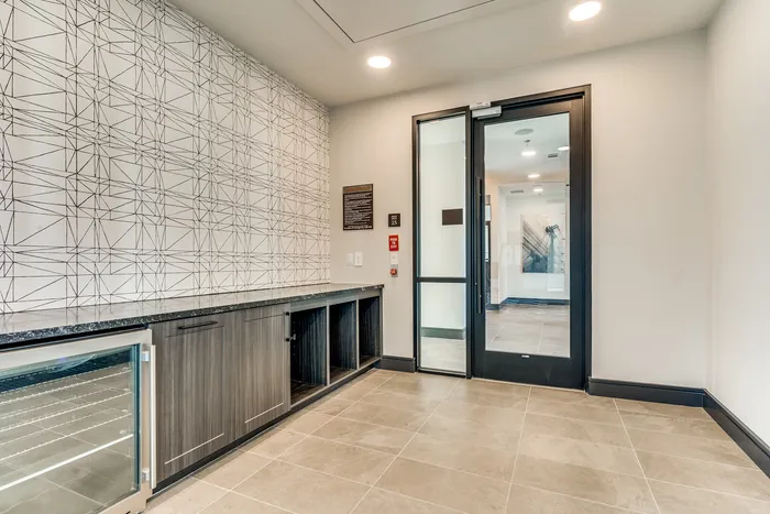 Modern entryway with sleek tile flooring, geometric feature wall, and stylish cabinetry leading to a luxurious living space.