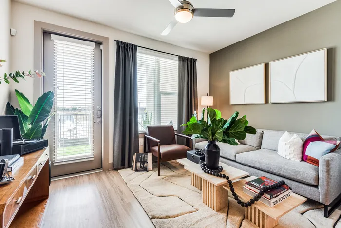 Bright and modern living room with sleek furniture, stylish decor, and lush green plants, offering a cozy and inviting atmosphere.