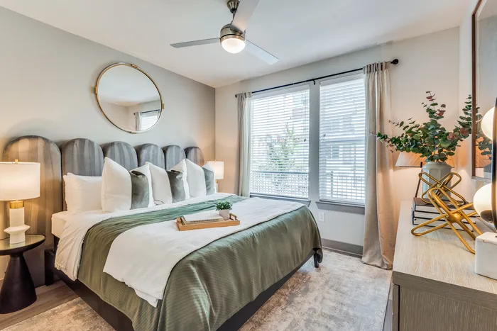 Elegant bedroom with a plush bed, modern decor, and abundant natural light, featuring a stylish headboard and cozy atmosphere.
