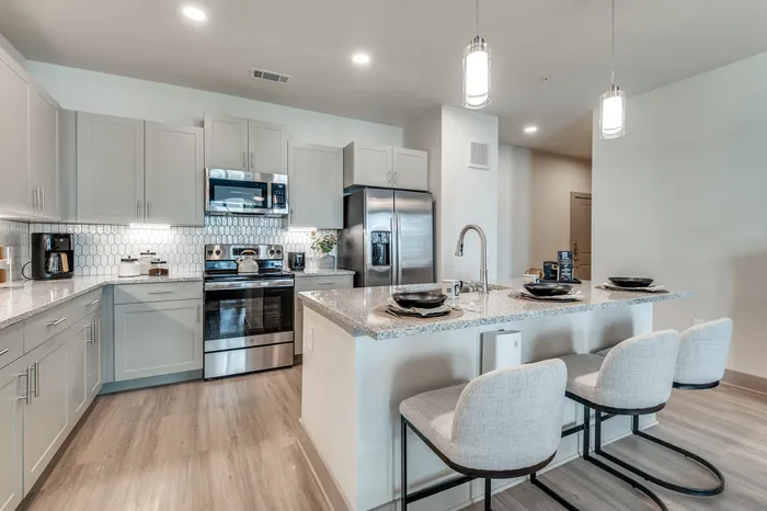 Modern kitchen with sleek stainless steel appliances, stylish grey cabinetry, and a chic breakfast bar with elegant barstools.