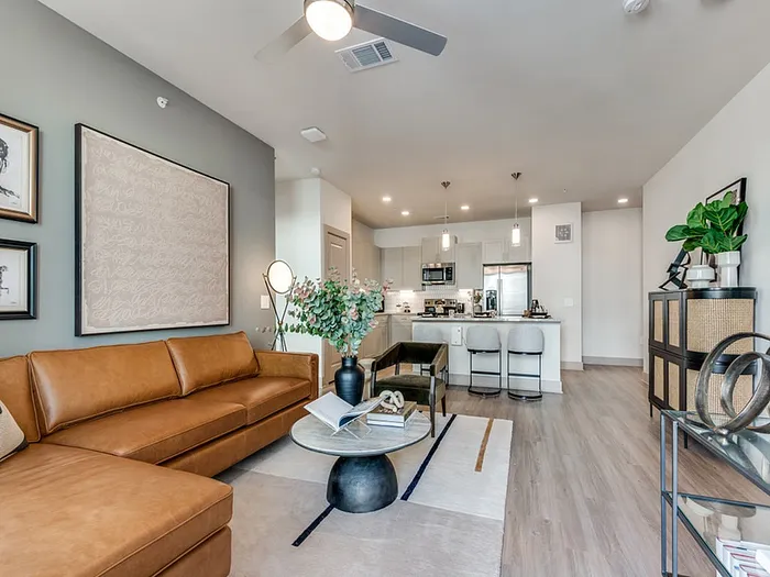 Contemporary open-plan living space with chic leather sofa, stylish decor, and modern kitchen with breakfast bar seating.