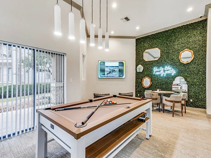Chic clubhouse with modern pool table, cozy seating, and vibrant neon sign accents.