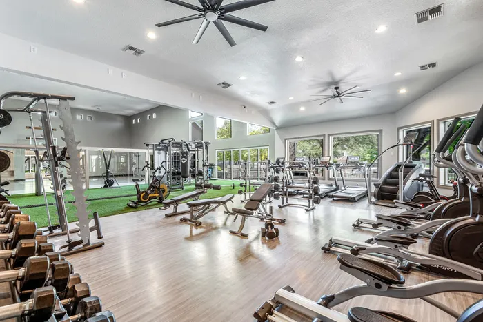 Spacious and modern gym featuring state-of-the-art fitness equipment, natural lighting, and sleek interiors.