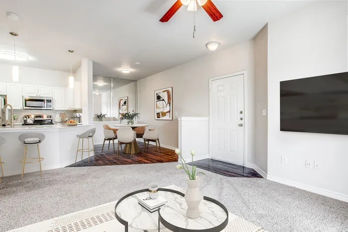 Contemporary open-plan living and kitchen area featuring elegant bar stools, sleek appliances, and a chic dining nook.