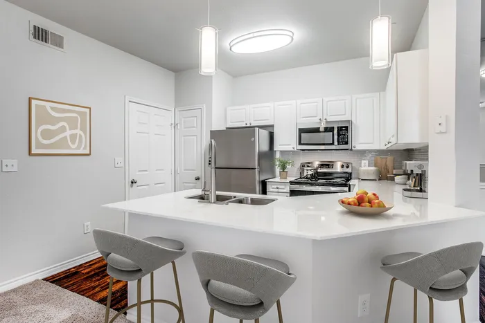 Modern kitchen with sleek appliances, elegant island seating, and chic decor in a bright, welcoming space.