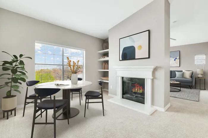 Bright and inviting apartment dining area with a modern table, chic chairs, and a cozy fireplace, perfect for relaxation and entertaining.
