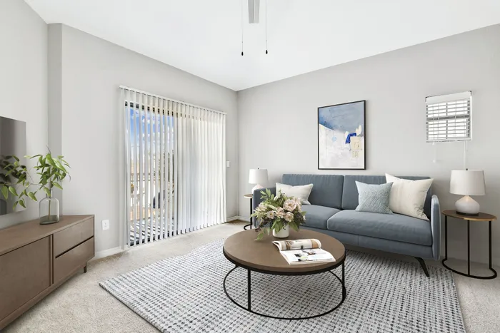 Inviting living room with modern decor, featuring a comfortable blue sofa, chic round coffee table, and elegant natural light from sliding glass doors.
