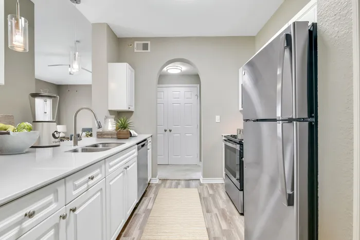 Modern kitchen with sleek stainless steel appliances, elegant white cabinetry, and stylish lighting features.
