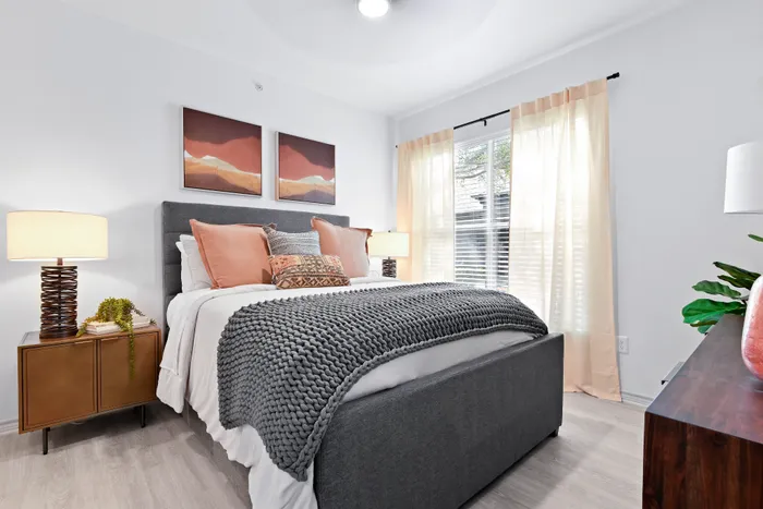 Bright and cozy bedroom featuring elegant decor, a plush gray bed, and soft ambient lighting.