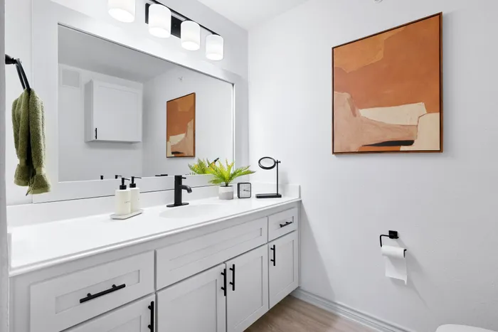 Chic bathroom featuring a sleek white vanity with modern fixtures and elegant wall art.