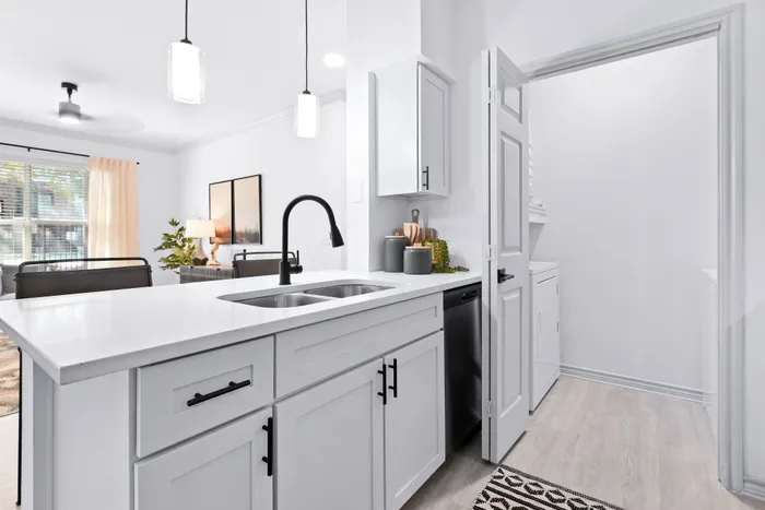 Bright and modern kitchen with sleek white cabinets, a stylish black faucet, and elegant pendant lighting, perfect for culinary creativity and social gatherings.