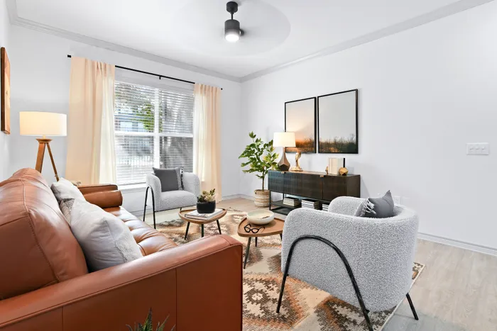 Inviting living room with modern decor, featuring a cozy leather sofa, stylish armchairs, and ample natural light.