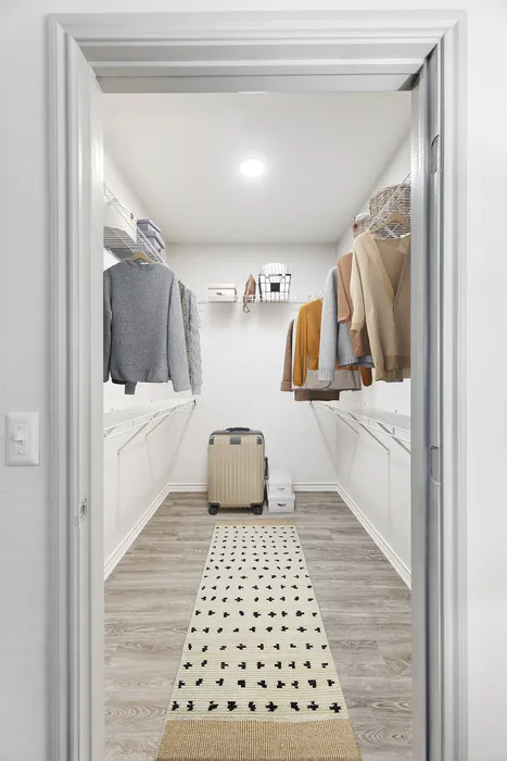 Spacious walk-in closet with modern shelving, stylish clothing display, and elegant wooden flooring.