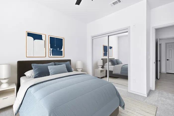 Inviting bedroom with plush blue bedding, modern mirrored closet, and abstract art accents, creating a serene and stylish atmosphere.