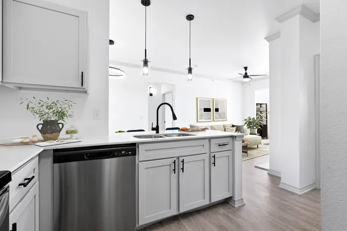 Modern open-concept kitchen with sleek white cabinetry, stainless steel appliances, and a view into a cozy living space with elegant decor.