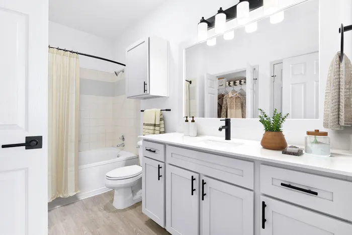 Bright and modern bathroom featuring elegant cabinetry, sleek fixtures, and a full bathtub with a soft shower curtain.