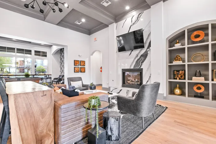 Interior leasing office with wall mounted tv, chairs, leather couch, and fireplace