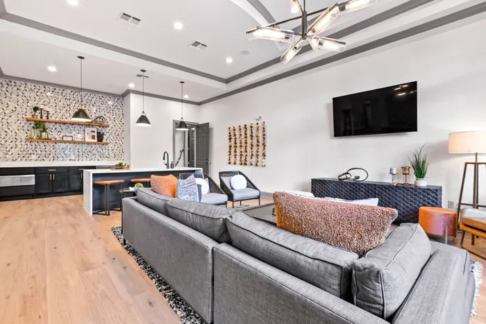 Interior leasing office with wall mounted tv, chairs, leather couch, and fireplace