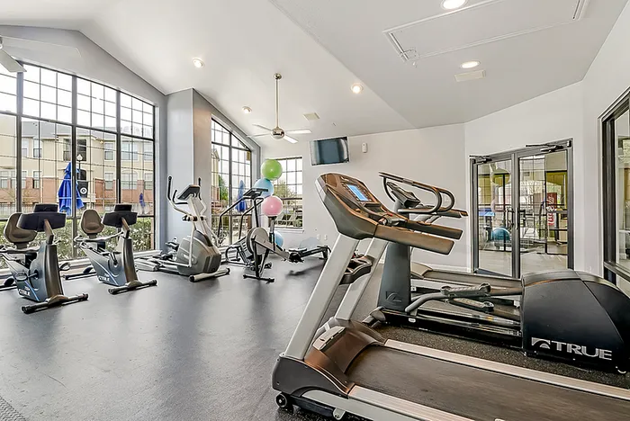 Fitness center with cardio machines, expansive weindows, and ceiling fans