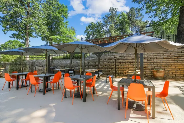Charming outdoor patio with vibrant orange chairs and shaded tables, perfect for relaxation and social gatherings.