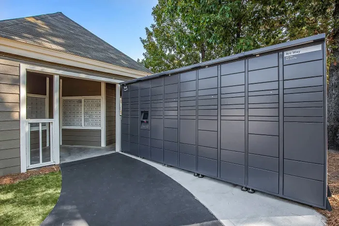 Modern package locker station at an inviting community entrance, surrounded by lush greenery, offering convenient secure delivery options.